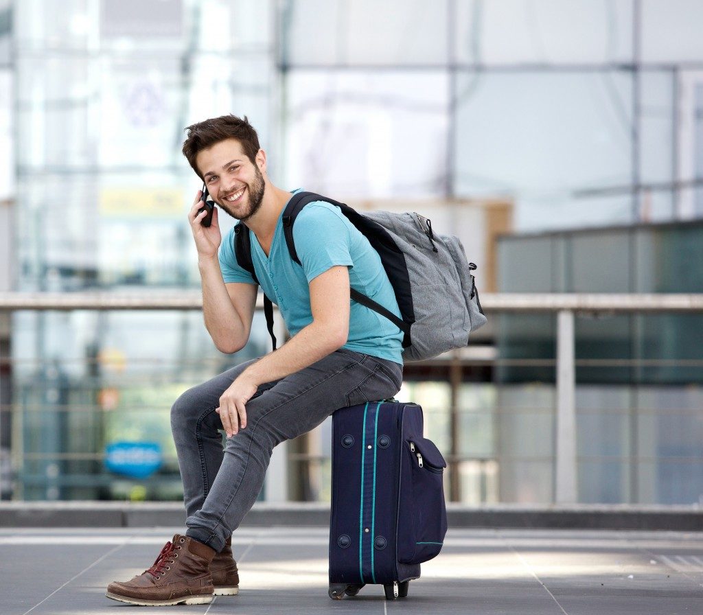 young man sitting on suitcase