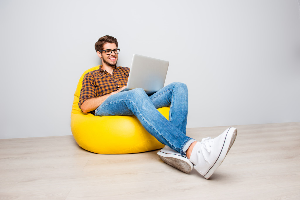 Man using laptop while sitting on yellow chair