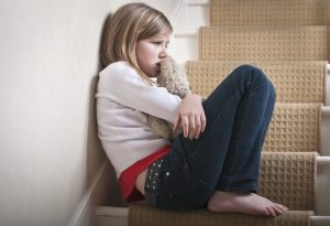 child hugging her stuffed toy while sitting in the stairs