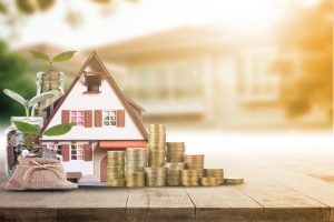 a miniature house model surrounded by coins representing a rental property