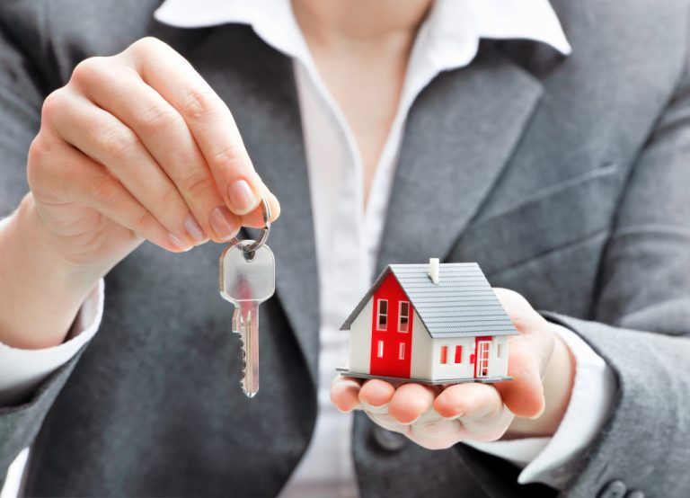 A real estate agent holding a miniature house and a key