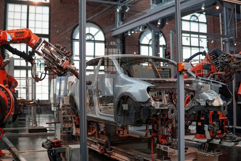 robot arm welding metal frames on an automotive assembly line